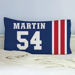Blue pillowcase with \“MARTIN\“ and the number \“54\“ in white, alongside three vertical red stripes. The pillow rests on a white bed with a cream blanket.