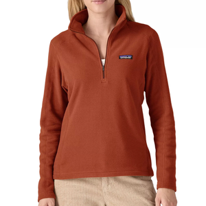 A rust-colored Patagonia Micro D Pullover made from soft fleece, featuring a quarter-zip design and the Patagonia logo on the chest, paired with beige corduroy pants.
