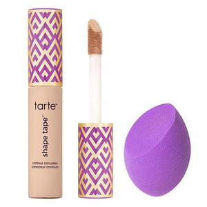Concealer with a sponge applicator next to a purple blending sponge.