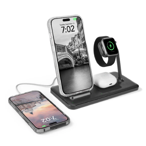 A wireless charging station holds a smartphone, smartwatch, and earbuds, with an additional phone charging beside it, displaying a digital time.