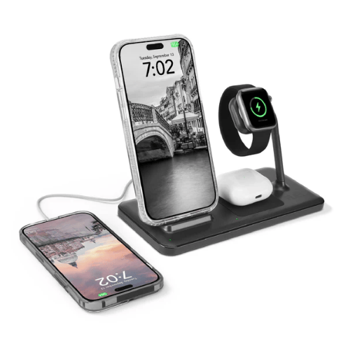 A wireless charging station holds a smartphone, smartwatch, and earbuds, with an additional phone charging beside it, displaying a digital time.