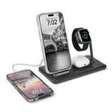 A wireless charging station holds a smartphone, smartwatch, and earbuds, with an additional phone charging beside it, displaying a digital time.