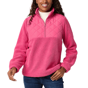 A woman is wearing a pink Sherpa quarter-zip pullover with a quilted upper chest and a fluffy lower half.