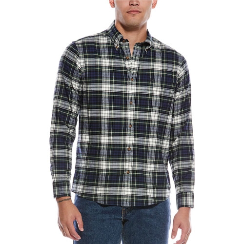 A man wears a long-sleeve, button-up plaid shirt with a blue, green, and white pattern, paired with blue jeans.