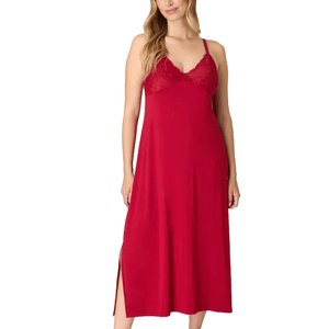 A woman is wearing a sleeveless red nightgown with lace detailing on the bodice and adjustable straps. The nightgown has a side slit.