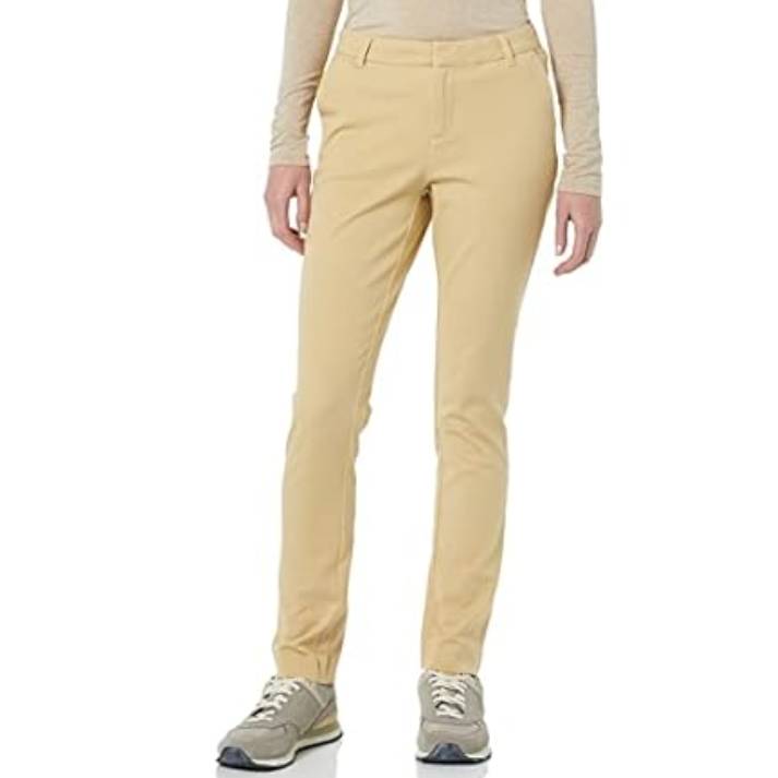 Amazon Essentials Women's Bi-Stretch Pant is a slim-fit, beige, ankle-length pant featuring a flat front and belt loops, paired with casual sneakers and a long-sleeve beige top.