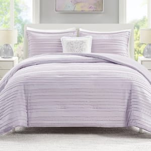 The JLA Home Ottie Comforter Set features a lavender comforter with horizontal textured lines, accompanied by matching pillow shams and a decorative white accent pillow with a floral design.