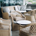 Outdoor wicker furniture including chairs with cushions and a sofa with a small round table.