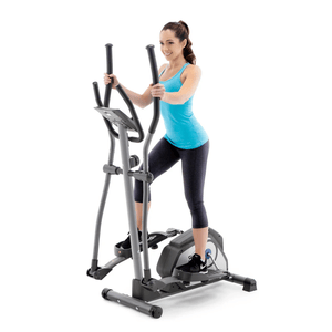 A woman exercises on a compact elliptical trainer, wearing a blue tank top and black leggings.