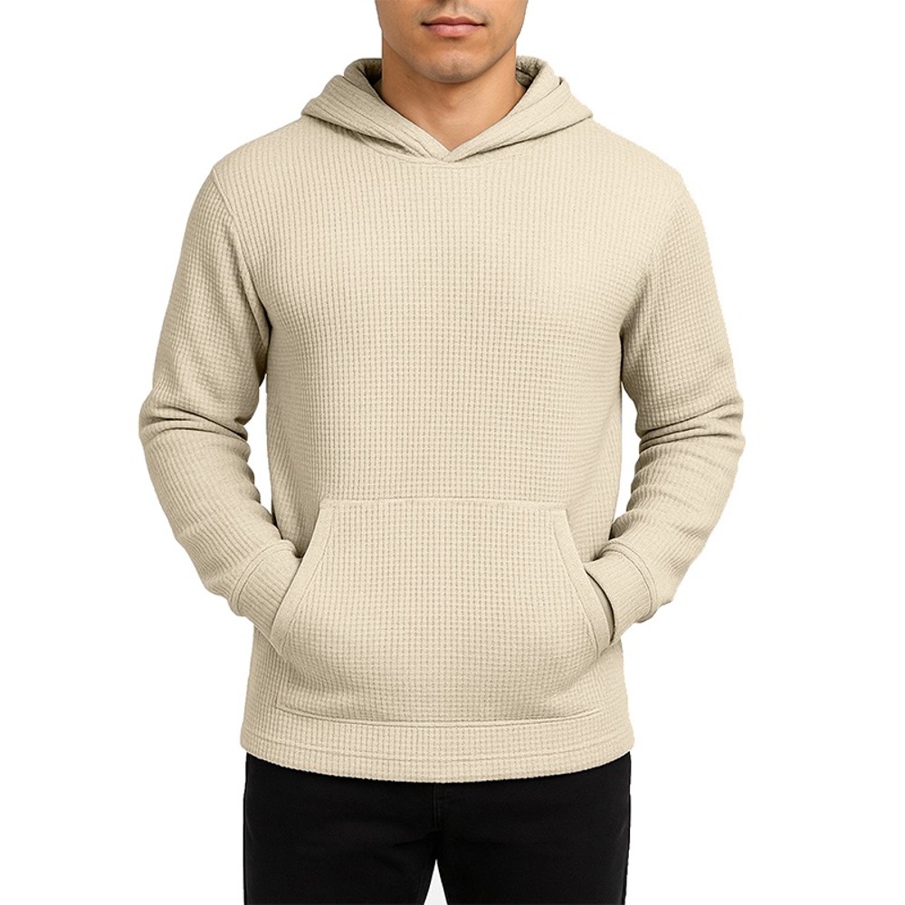 A beige, waffle-knit hoodie with a front pocket and long sleeves, paired with black pants.