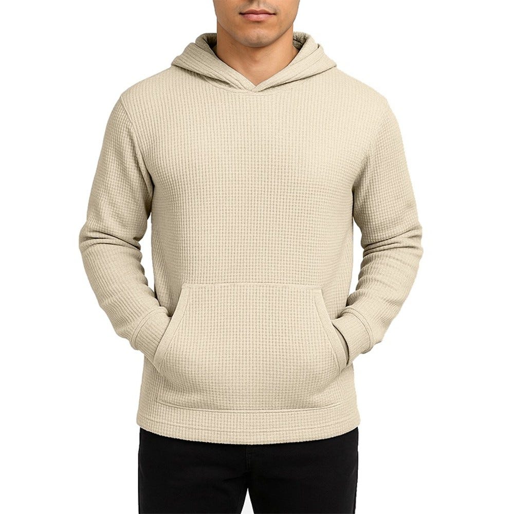 A beige, waffle-knit hoodie with a front pocket and long sleeves, paired with black pants.
