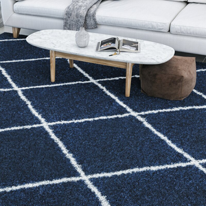 Navy shag geometric rug with a grid design of white intersecting lines, placed under a modern marble-topped coffee table and adjacent to a white sofa. Rug dimensions: 8' x 10'.