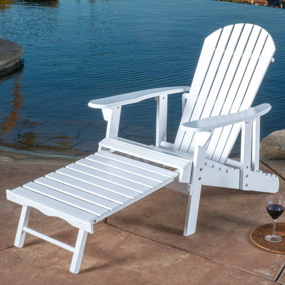 White Adirondack chair with an extended footrest, placed by a poolside with a glass of red wine on a coaster nearby.