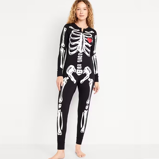 A person is wearing black one-piece pajamas with a white skeleton print design, representing a human ribcage and bones.