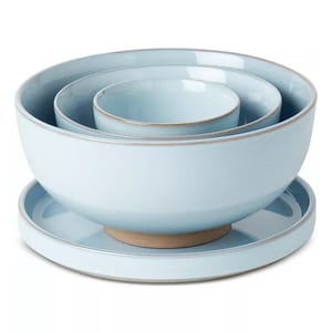 A light blue 4-piece stoneware nesting bowl set with a minimalist design, featuring three nested bowls of varying sizes and a matching plate at the base, ideal for serving or kitchen use.