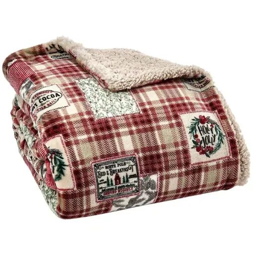 A plaid sherpa throw blanket featuring holiday-themed patches with designs like \“Hot Cocoa\“ and \“Holly Jolly\“.