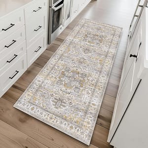 A patterned runner rug with a vintage design featuring grey, gold, and beige tones placed on a light wood floor in a kitchen setting with white cabinetry.