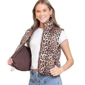 A woman is wearing a reversible puffer vest with a leopard print on one side and a solid brown color on the other.