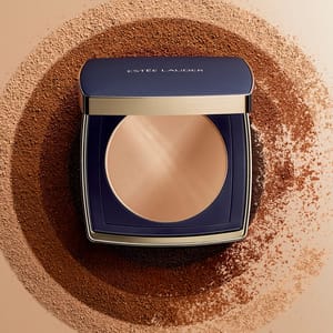 Estee Lauder powder compact set against a backdrop of varying powder shades in a circular pattern, highlighting its color and finish.