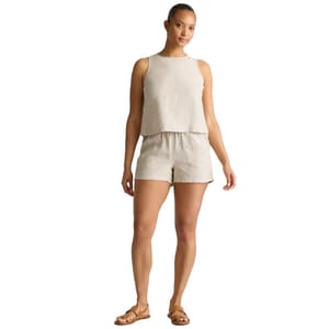 Woman wearing a beige sleeveless top and matching shorts, paired with brown sandals.