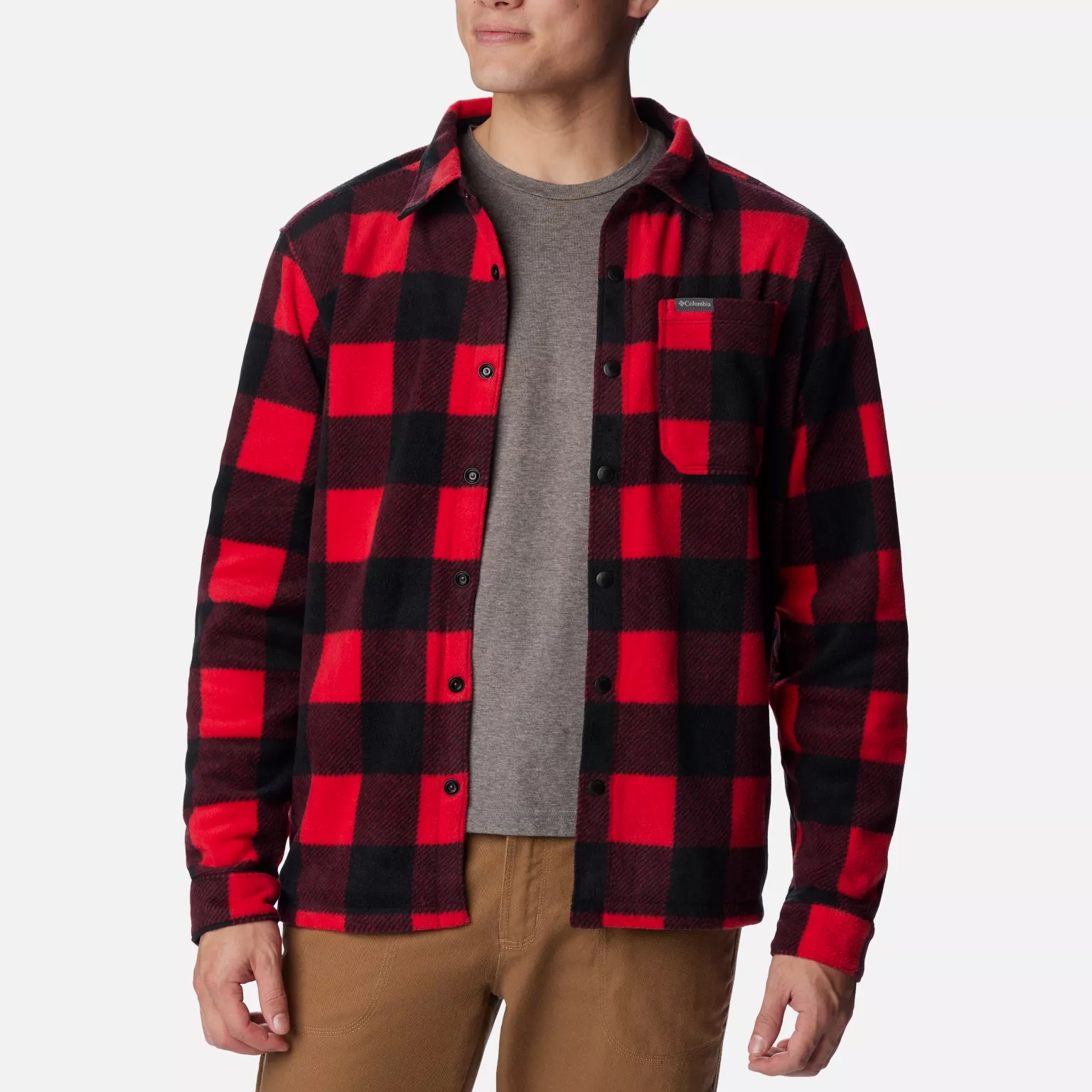 A man wearing a red and black checkered flannel shirt over a gray T-shirt paired with khaki pants.