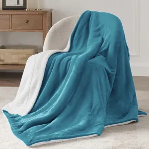 A plush blue throw blanket with a white sherpa lining draped over a cream-colored chair. In the background, there's a wooden side table with a basket underneath.