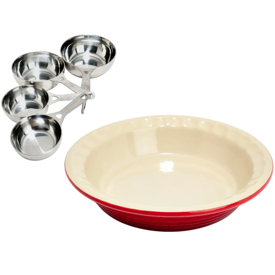 A set of stainless steel measuring cups is next to a red and cream ceramic pie dish with a scalloped edge.
