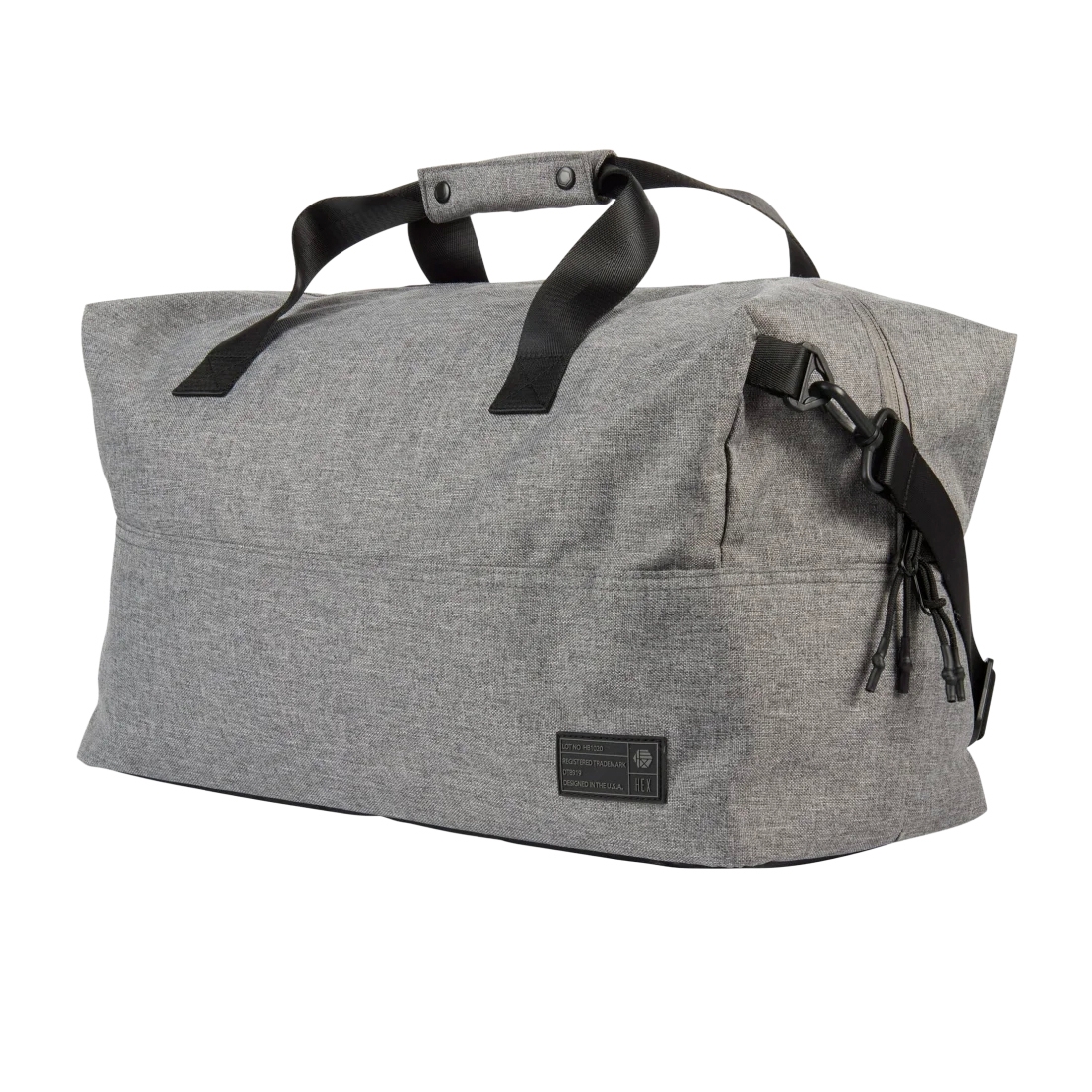 A gray duffel bag with black handles, featuring a side zipper and buckle closure. The bag also displays a small black patch with text near the bottom corner.