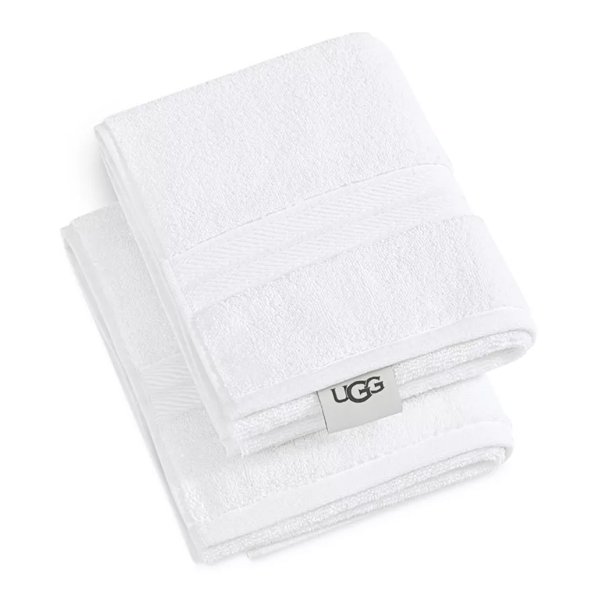 A pair of white UGG hand towels featuring a subtle textured band design and an UGG brand tag. The towels have a simple, elegant appearance suitable for bathroom use.