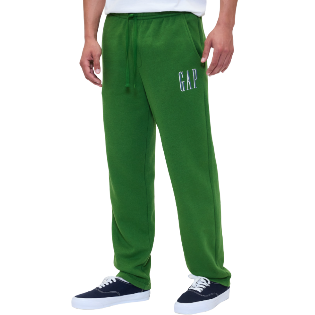 Green sweatpants with a drawstring waist, featuring the word \“GAP\“ on the left side, worn with navy and white sneakers.