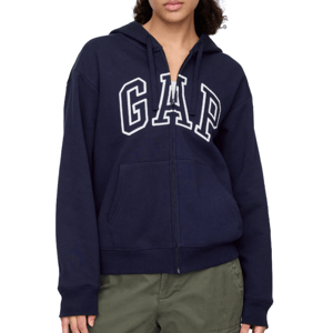 A person wears a navy blue GAP hoodie with a zip-up front and a large front pocket, paired with olive green pants.