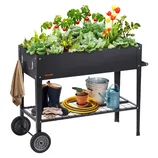 A raised garden bed with wheels, growing various plants like lettuce, tomatoes, and tulips, features storage below with gardening tools, a watering can, hose, boots, and gloves.