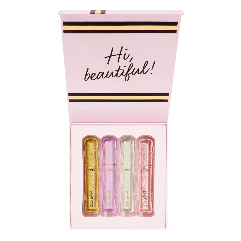 A set of four pastel-colored mascaras from Tarte, displayed in a pink box with the greeting \“Hi, beautiful!\“ on the lid. The tubes are in gold, purple, silver, and pink hues.
