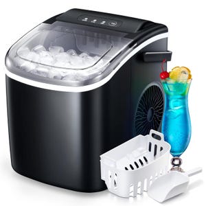 A compact black ice maker with a transparent lid, filled with ice cubes, accompanied by a white basket and scooper, and a blue cocktail with fruit garnish.