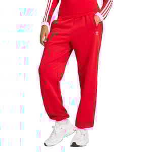 Adidas Women's Fleece Joggers in bright red feature a relaxed fit with an elastic waistband and cuffs, side pockets, and the iconic Adidas logo on the thigh. The joggers are paired with white sneakers and a matching top with striped sleeves.