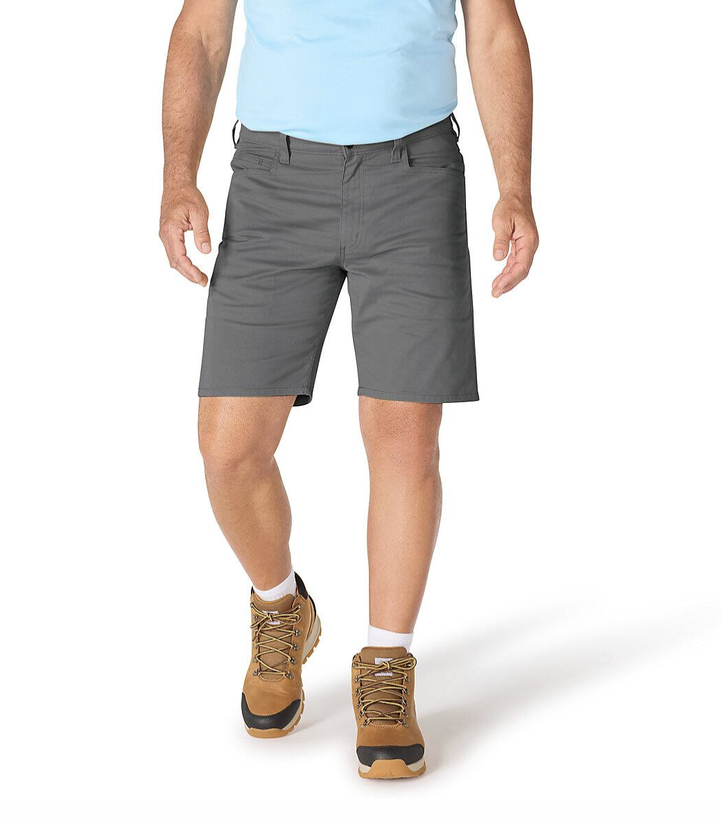 A person is wearing gray shorts, a light blue shirt, and brown hiking boots with white socks.