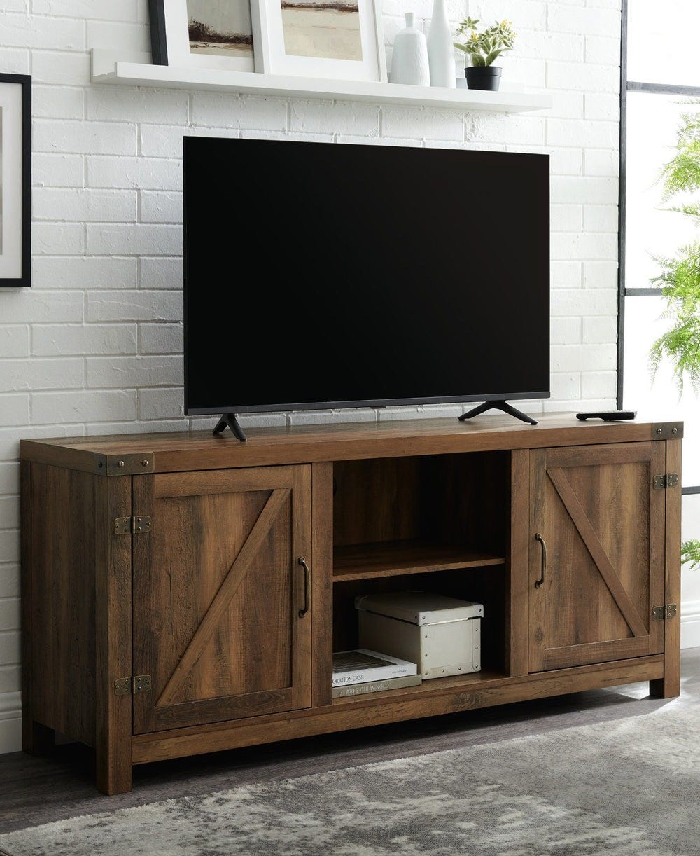 Wooden TV stand with a rustic design featuring two side cabinets and a central open shelf, supporting a flat-screen TV.