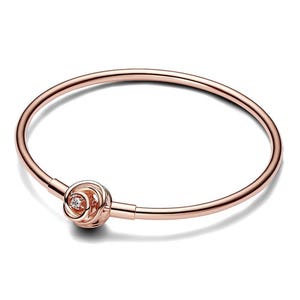 A sleek 14K rose gold plated bangle with a minimalist design featuring a single cubic zirconia nestled within a central knot accent.