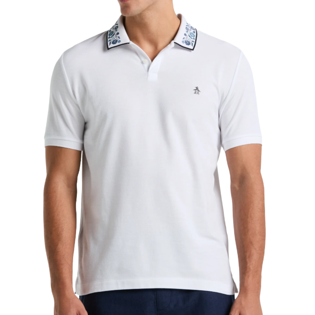 White polo shirt with a floral-patterned collar and a small penguin logo on the chest, paired with dark pants.
