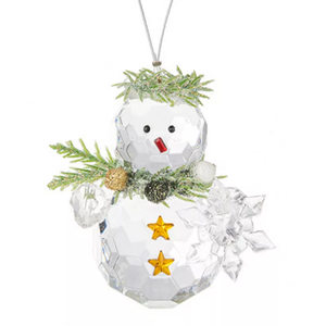 A faceted glass snowman ornament adorned with a red nose, black eyes, green pine-like accents, gold buttons, and a clear snowflake on the side, hanging from a silver loop.