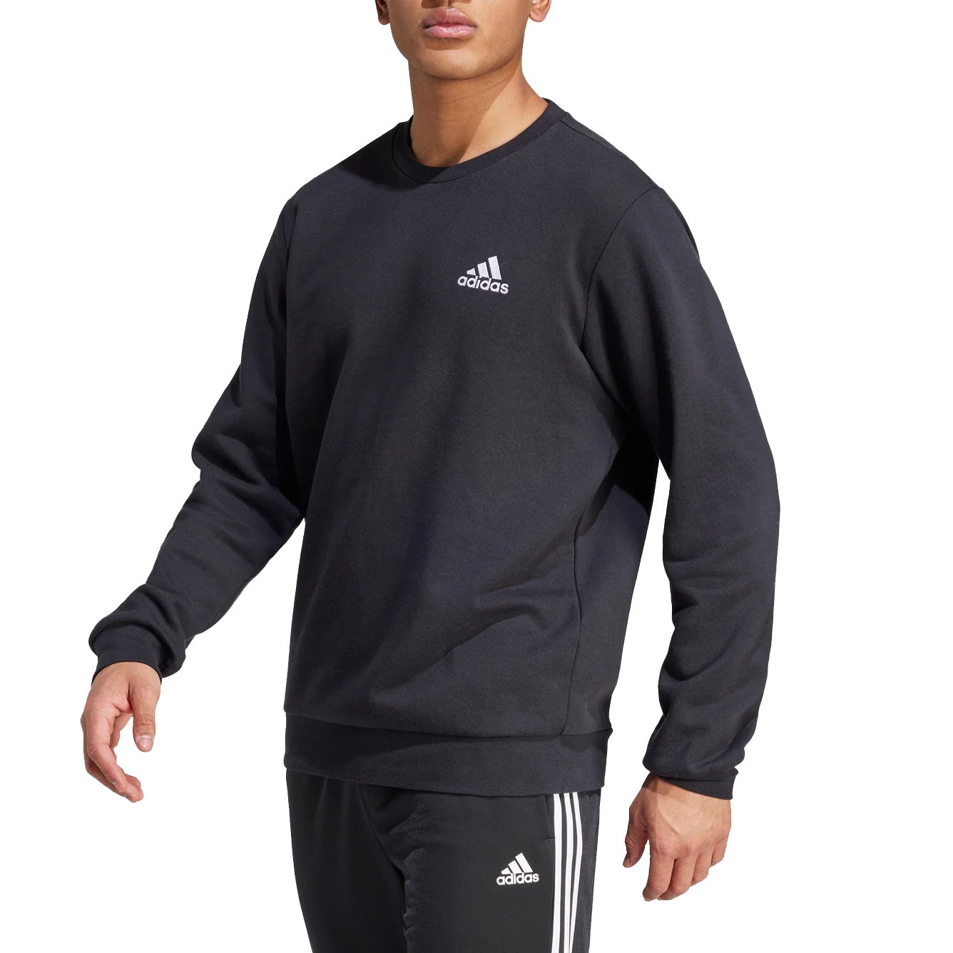 Adidas Men's Essentials Fleece Sweatshirt is black with a small white Adidas logo on the chest. It features a crewneck design and long sleeves, offering a sporty and casual look.