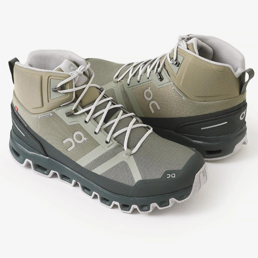 A pair of olive green and gray hiking boots with laces.