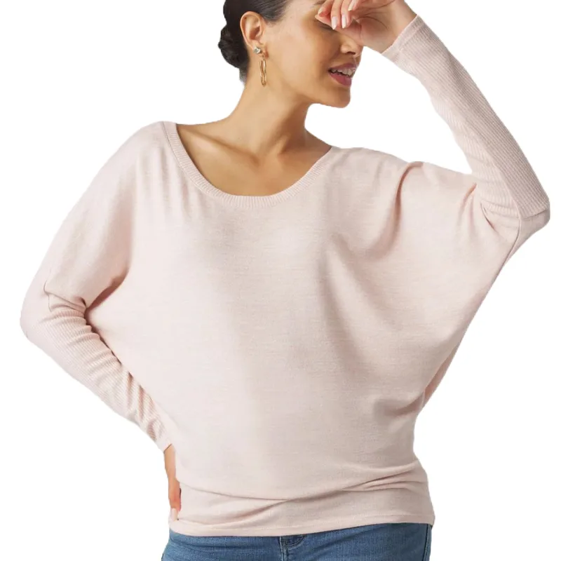 A pale pink, long-sleeve ribbed tunic sweater with a relaxed fit and dolman sleeves, worn over blue jeans.