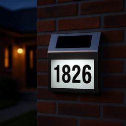 Solar-powered LED house number sign displaying \“1826\“ mounted on a brick wall, illuminating the numbers for visibility at night.