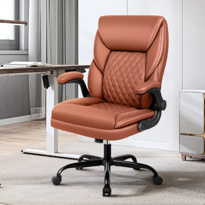 A brown leather office chair with quilted stitching, armrests, and a swivel base on casters, positioned next to a modern desk in a well-lit room.