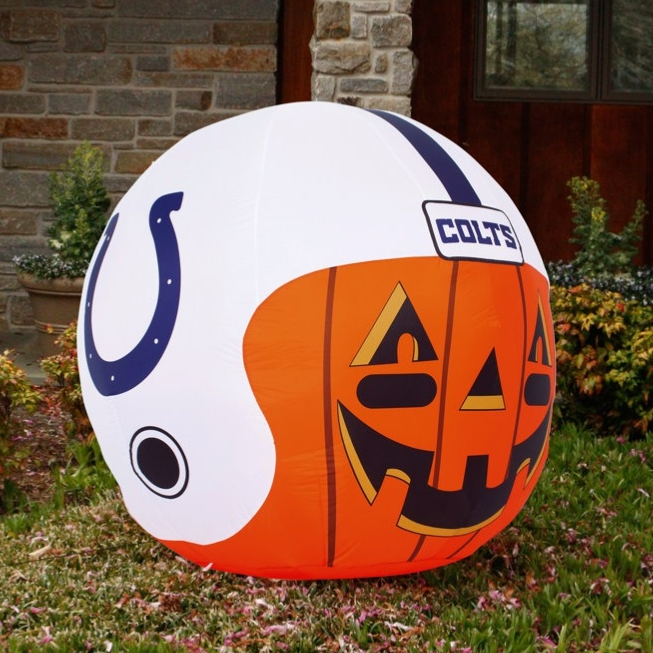Inflatable Halloween decoration shaped as a football helmet with a jack-o'-lantern face, featuring the Colts logo and colors, displayed on a lawn in front of a house.