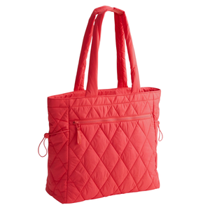 A red quilted tote bag with large padded handles, featuring a diamond pattern and a front zipper pocket.
