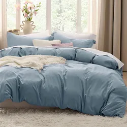 A neatly arranged bed with a light blue duvet cover, matching pillows, and a white knit throw blanket on a fluffy rug, with decorative pillows and a vase of flowers nearby.