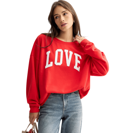 A person wearing a red sweatshirt with \āLOVE\ā printed in large white letters pairs it with blue jeans. They hold a handbag and have long hair.