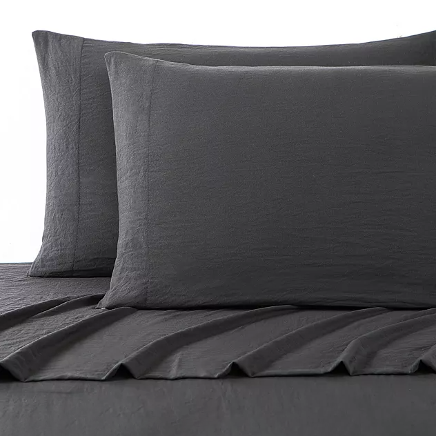 A set of dark grey UGG sheets and pillowcases with a textured design on a bed.